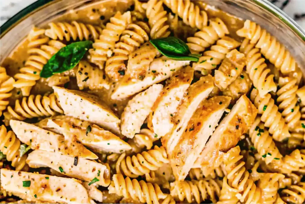 Close-up of Garlic Parmesan Chicken Pasta with sliced chicken, creamy sauce, and fresh basil garnish.