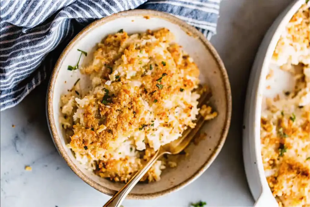 A serving of Million Dollar Chicken Casserole with a golden, crunchy topping in a small bowl with a fork.