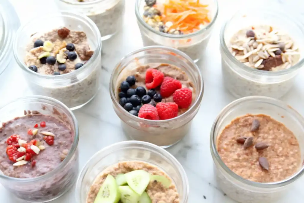 Multiple jars of overnight oats with various toppings like berries, cucumbers, and seeds.