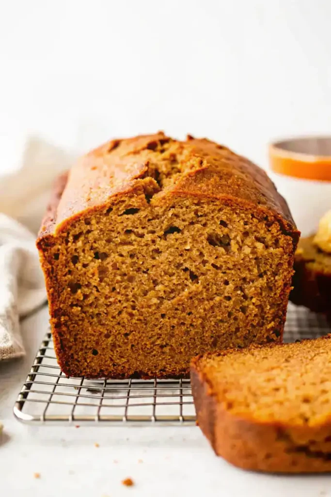 Close-up of a sliced sweet potato bread showing its golden crumb on a cooling rack.