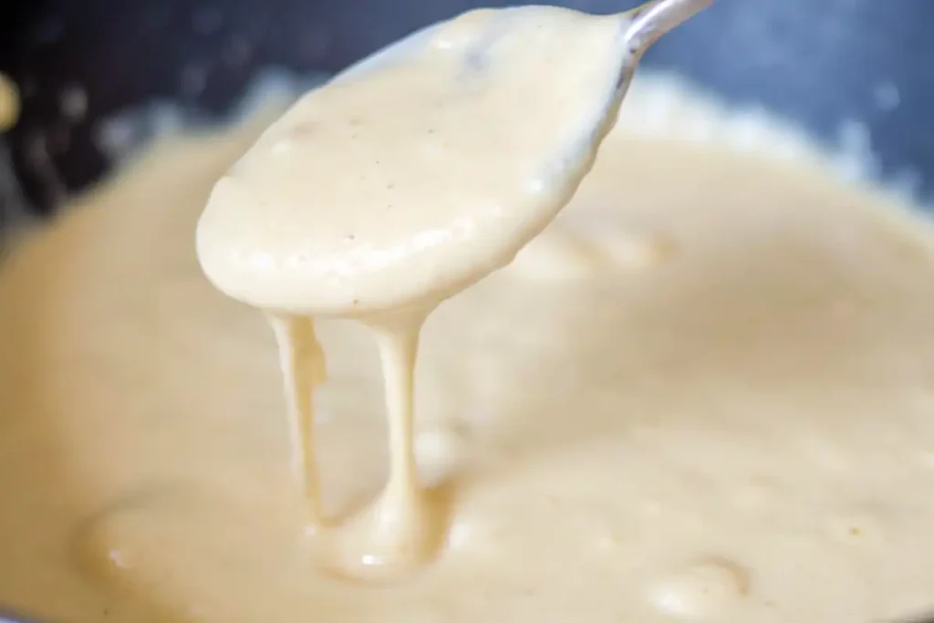 A creamy garlic Parmesan sauce dripping from a spoon