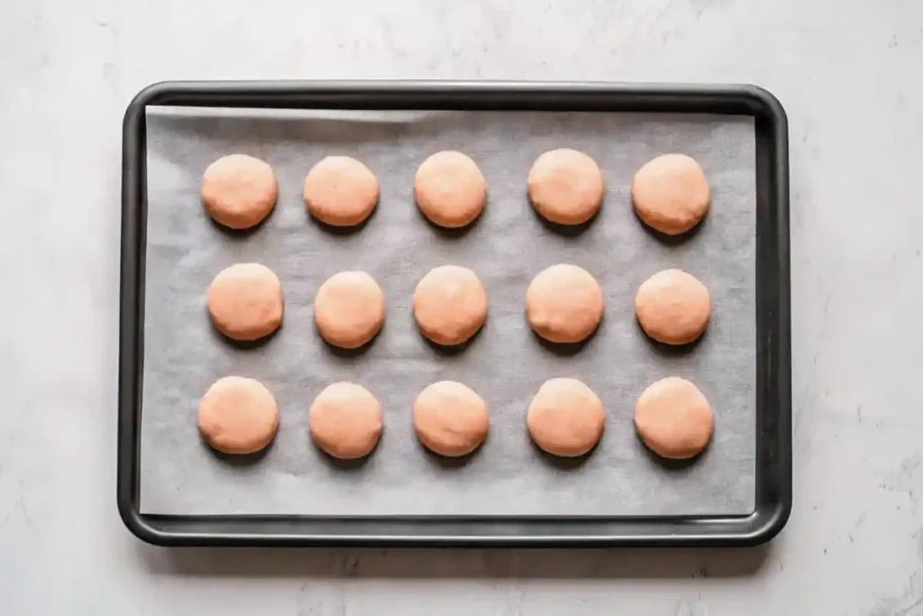 Baked macaron shells on a parchment-lined baking tray, ready for filling.