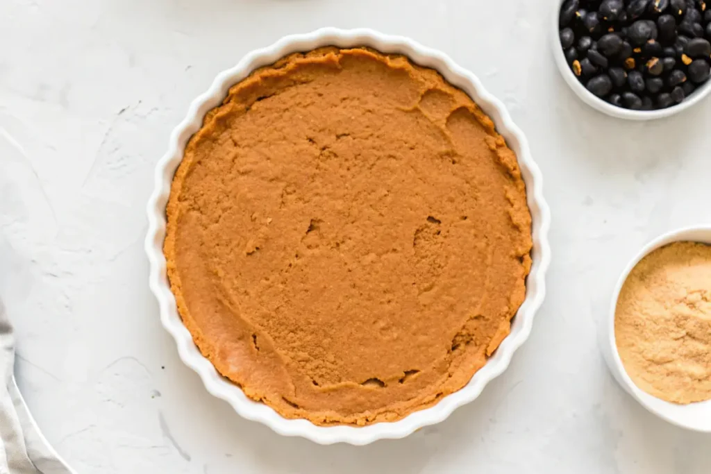 Smooth refried beans spread evenly in a white pie dish, ready for layering.